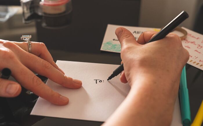 Person writing a message on an envelope, illustrating shocking experiences people have lived through moments.