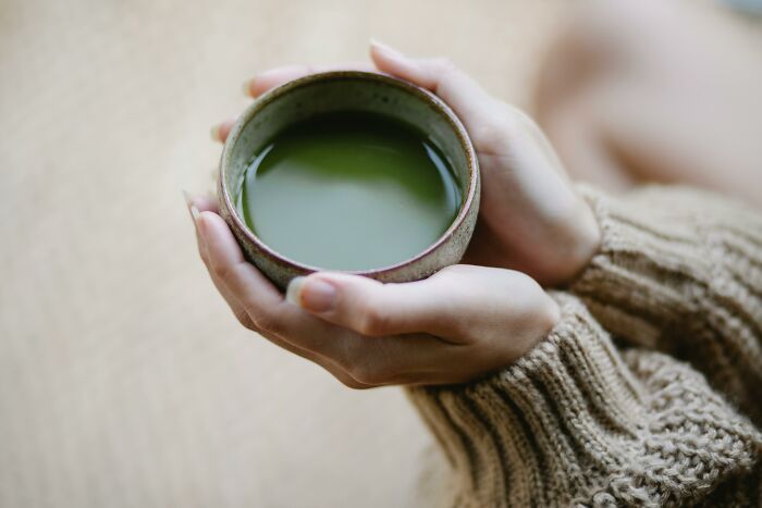 Person holding a ceramic cup of green tea, illustrating examples of placebo effect in real life scenarios.