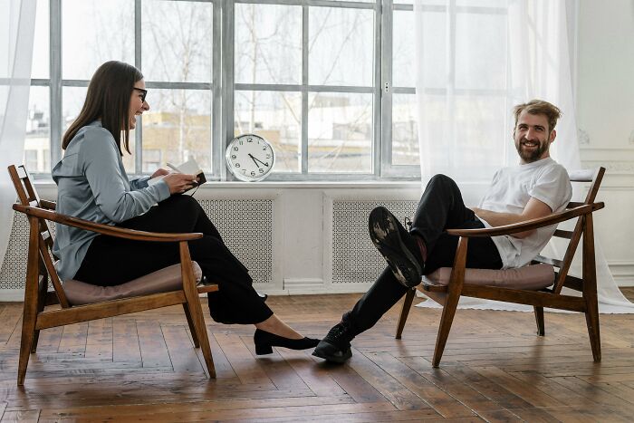 Two people sitting in wooden chairs by a window having a casual conversation about life lemons advice.