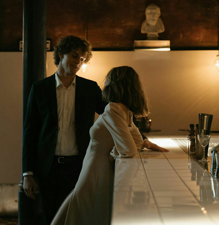 A woman leaning on a bar looking up at a man standing close, highlighting moments women felt instantly unsafe with men.