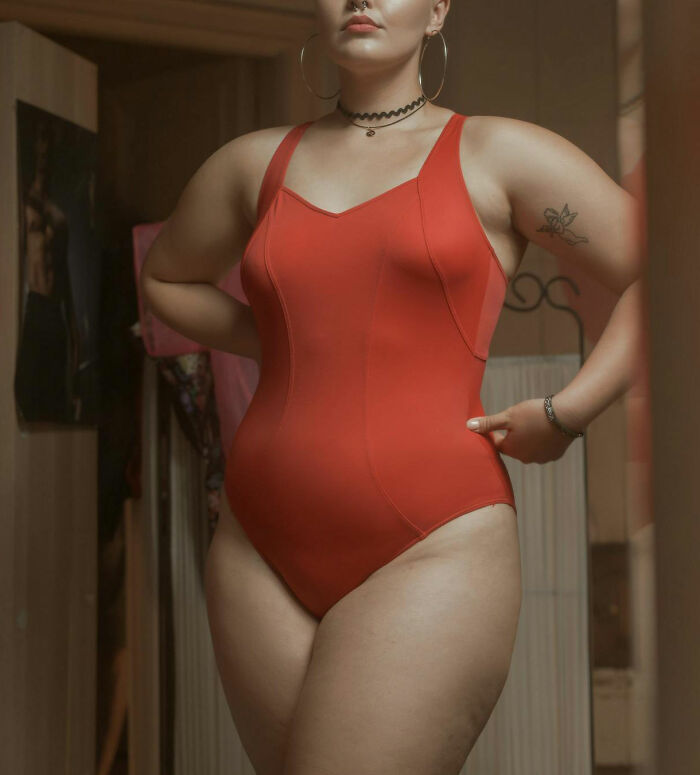 Woman in a red swimsuit standing confidently indoors, representing women sharing questions they would ask men without judgment.