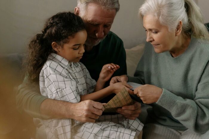 Older grandparents giving money to their granddaughter while feeling jealous of ex-in-laws' generosity.