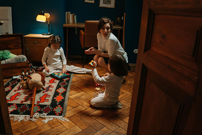 A woman discusses with two children on the floor, highlighting siblings turning on sister over shelter refusal.