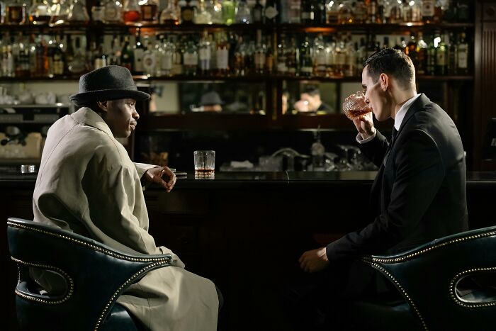 Two men in a bar having a deep conversation, illustrating bartender stories beyond just pouring drinks.
