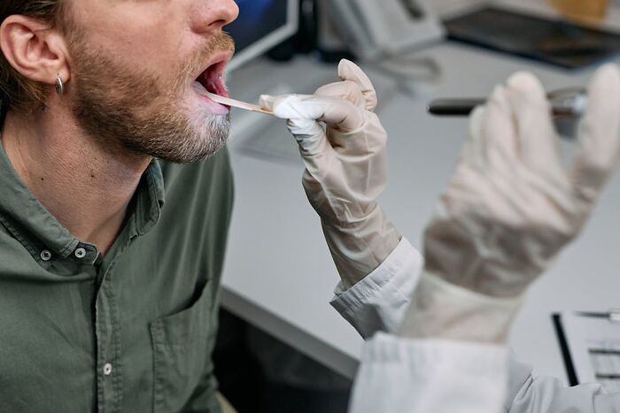Man in a medical setting having a genetic test with a swab, illustrating the concept of really good or really bad genes.