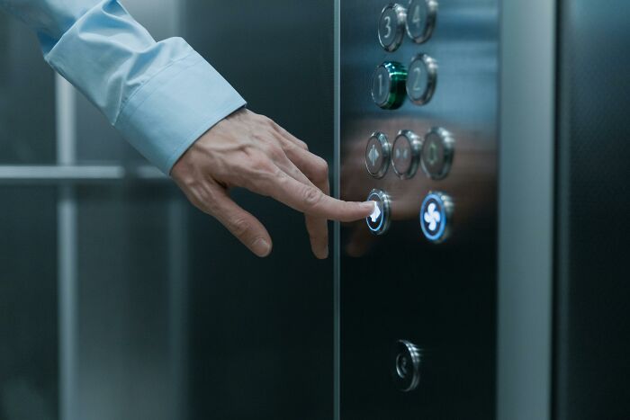 Person pressing an elevator button, illustrating appalling facts people unaware about common everyday actions.
