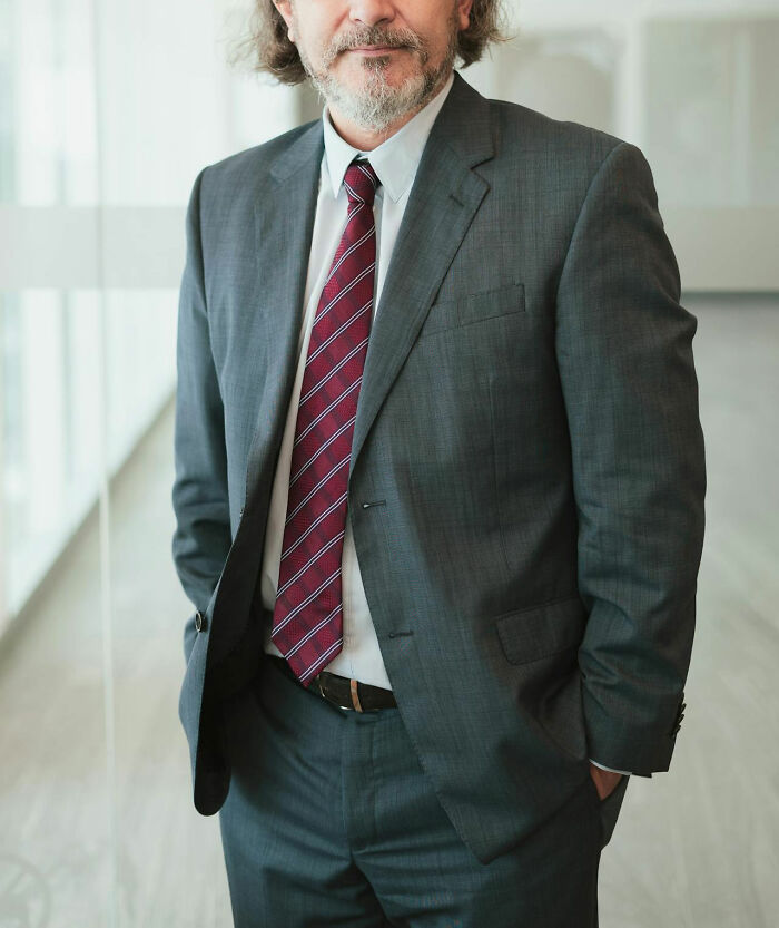 Middle-aged man in suit and striped tie standing confidently indoors, illustrating teachers unhinged but effective methods
