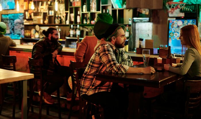 Two bartenders in a cozy bar setting engaging with customers, showing that the job is more than just pouring drinks.