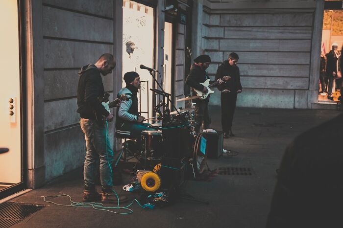 Street musicians performing with guitars and drums on an urban sidewalk, showing moments that improved quality of life.