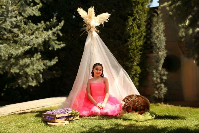 Young girl in a pink dress sitting under a decorative canopy outdoors, illustrating absurd things people were told growing up.