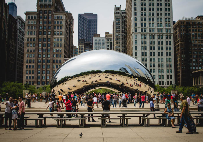 Crowds at Chicago&rsquo;s Cloud Gate sculpture highlighting decline in US tourism and its impact on money loss in the sector.