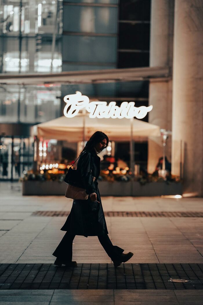 Woman walking alone at night in an urban area, conveying a feeling of safety contrasted with moments of feeling instantly unsafe with a man.