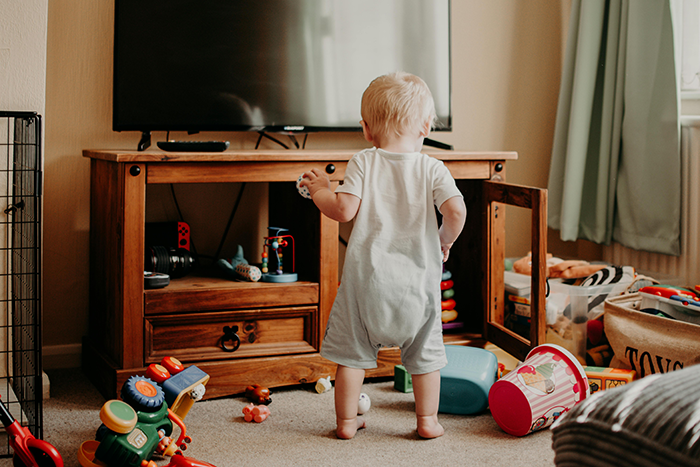 Toddler playing in a messy room filled with scattered toys, illustrating chaos caused by mom&rsquo;s new boyfriend&rsquo;s kids wrecking teen&rsquo;s space.