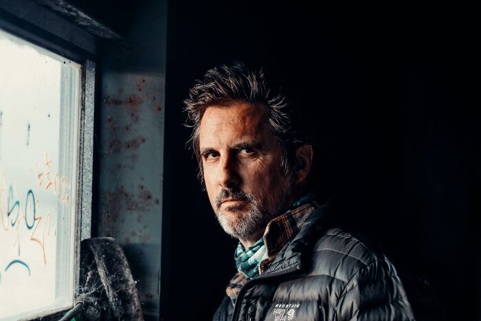 Middle-aged man with gray hair and beard, wearing a jacket, showing body changes that indicate aging clearly.