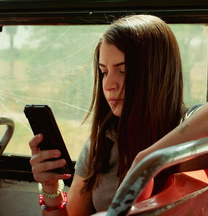 Young woman on a bus focused on her smartphone, reflecting on common boomer opinions that people agree with.
