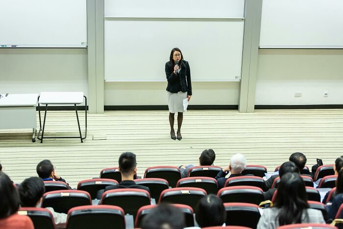 A woman speaking to an audience in a lecture hall during Teacher Appreciation Week event in 2025.