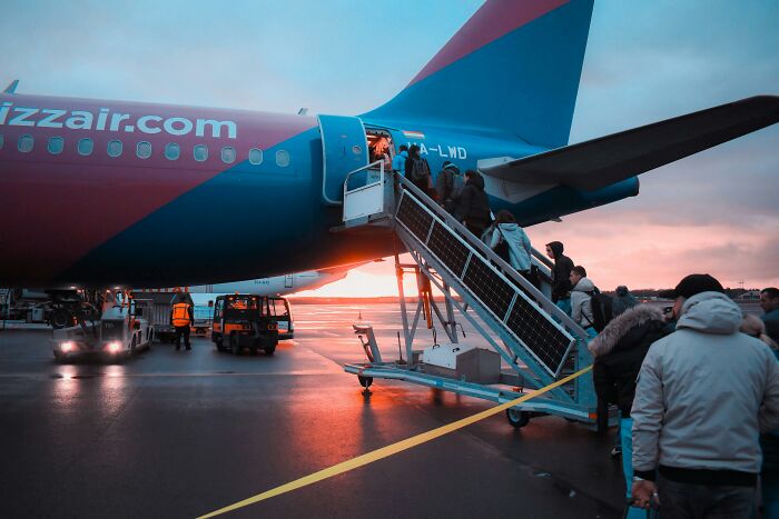 Passengers boarding a plane at sunset, illustrating common passenger habits that annoy flight attendants.