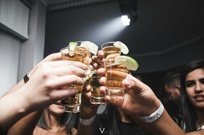 Group of people toasting with tequila shots garnished with lime, illustrating placebo effect in social drinking contexts.