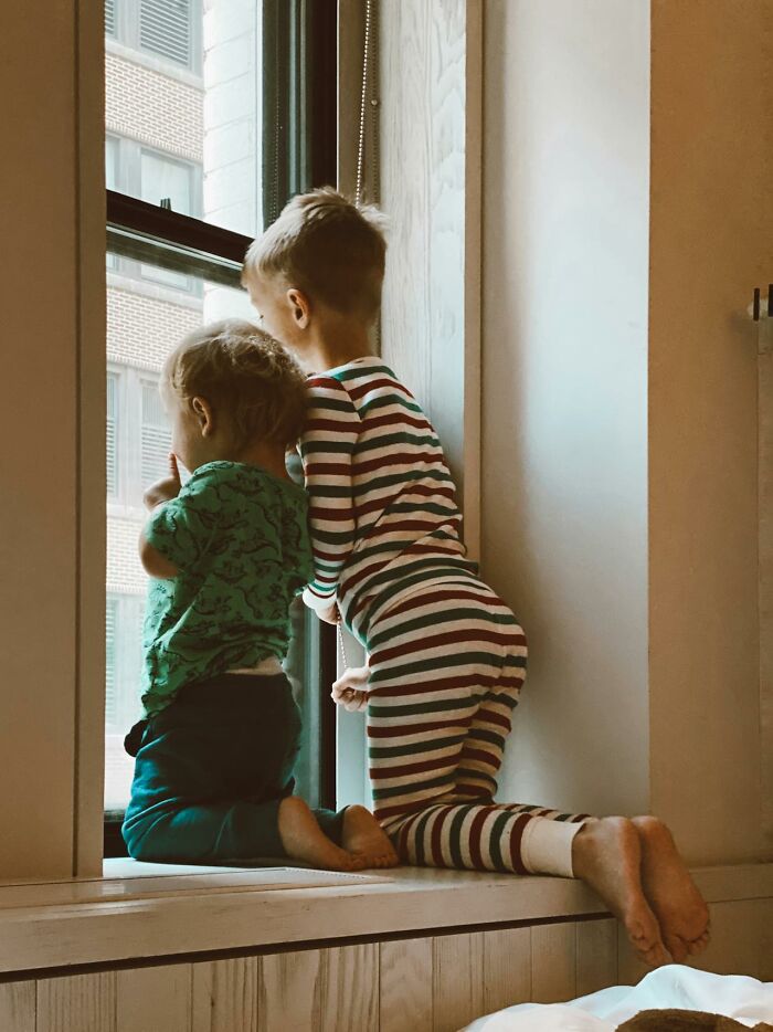 Two young children kneeling by a window looking outside, illustrating a calm moment unrelated to serotonin syndrome facts.