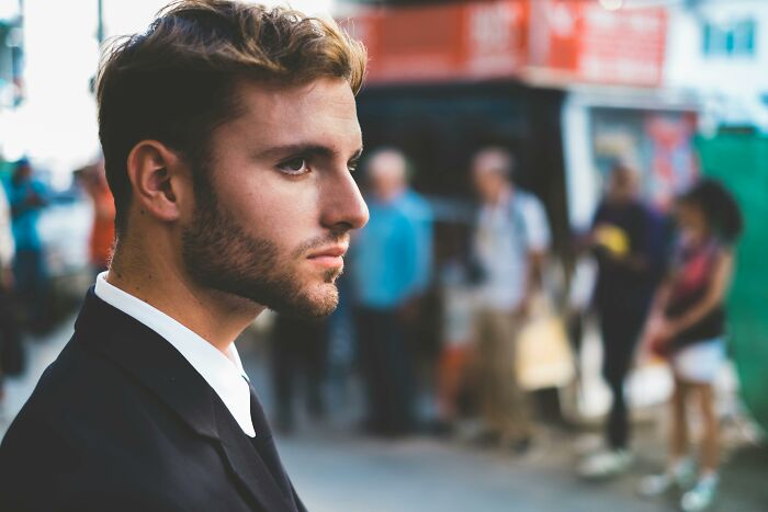 Young man in a suit looking thoughtful outdoors, concept for plastic surgeons discussing cosmetic procedures choices.