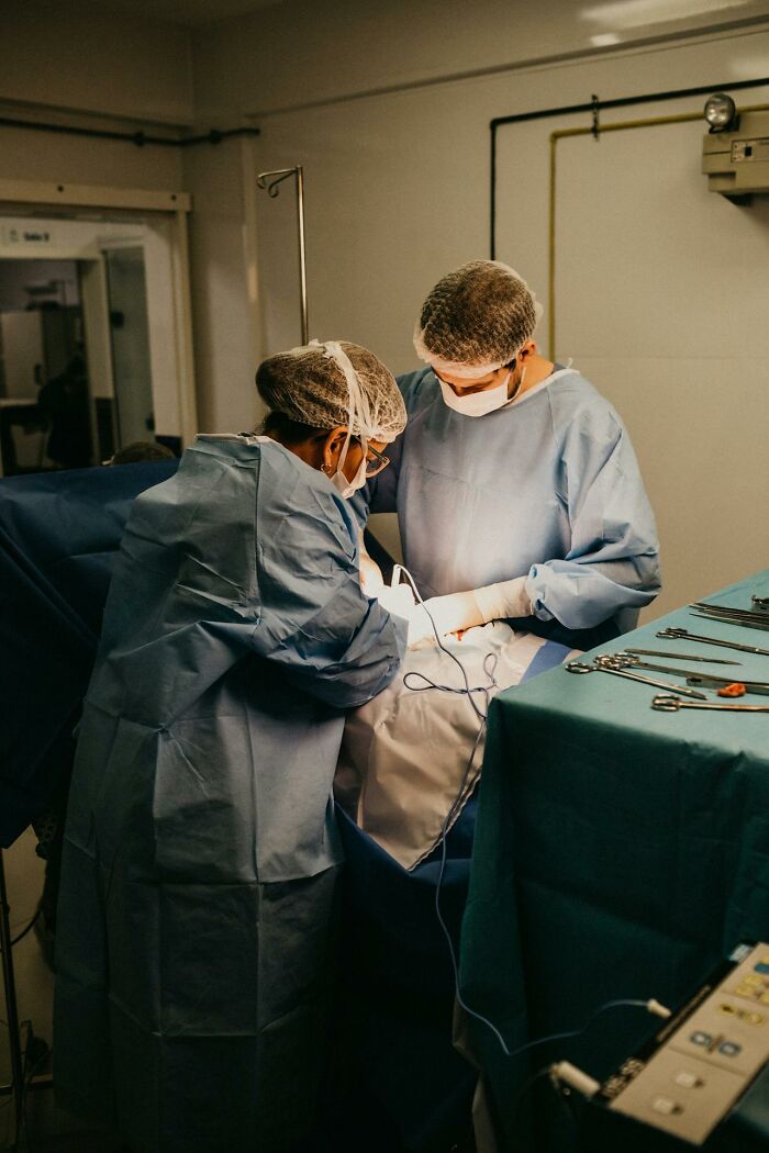 Two surgeons in protective gear performing surgery in a sterile operating room with medical instruments nearby, related to serotonin syndrome.