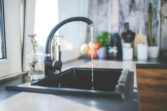 Modern kitchen sink with running water and small flower vase, illustrating mind-blowing cultural differences in daily living.