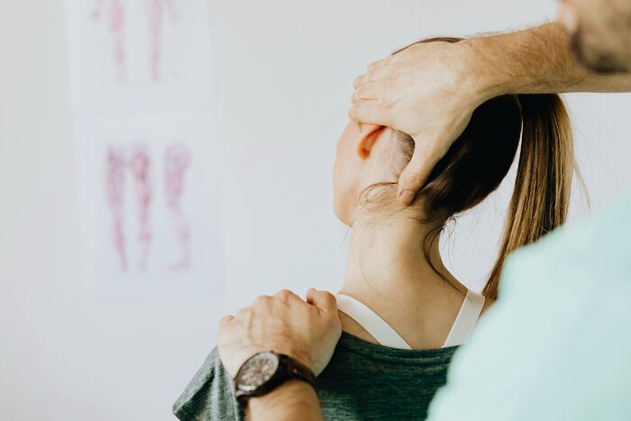Chiropractor adjusting woman's neck, illustrating placebo effect examples in real life with physical therapy treatment.