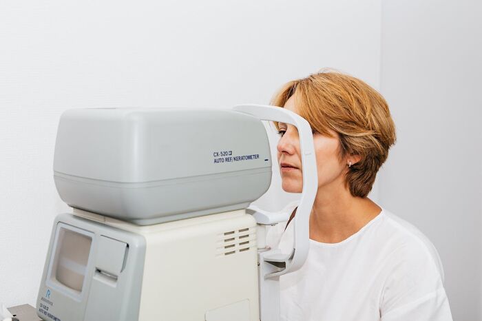 Woman using an eye exam machine, highlighting improvements that enhanced her quality of life significantly.