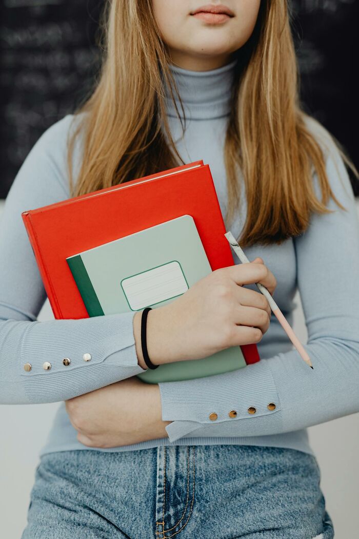 Young Gen Z woman holding notebooks and pencil, representing challenges middle class is over discussions.