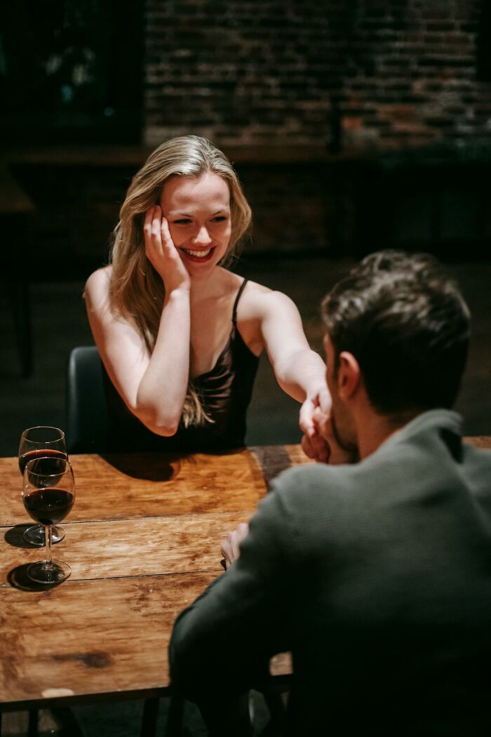 A woman smiling and holding hands with a man during a date, capturing women questions to men in a candid moment.
