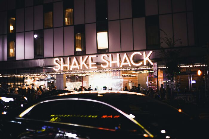 Shake Shack restaurant at night with people outside, illustrating companies on a people share bad list.