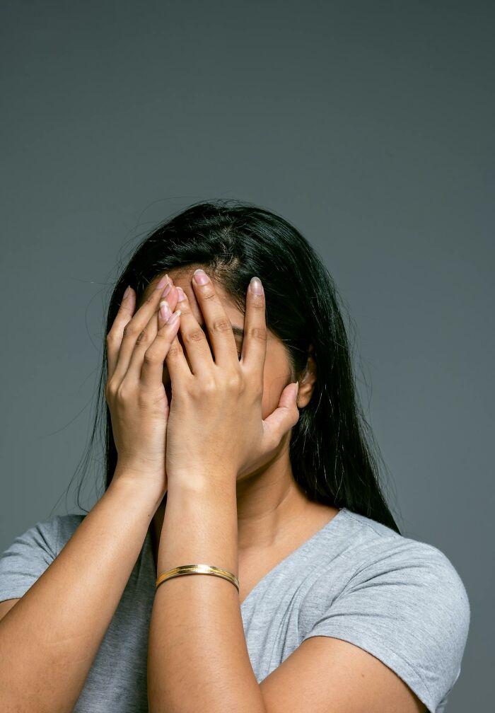 Person covering face with hands looking distressed, illustrating symptoms related to serotonin syndrome effects.