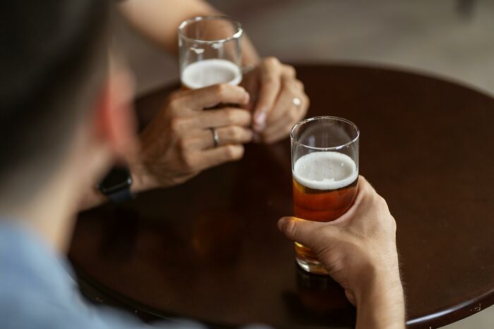 Two people holding beer glasses at a bar table, illustrating bartender stories beyond just pouring drinks.