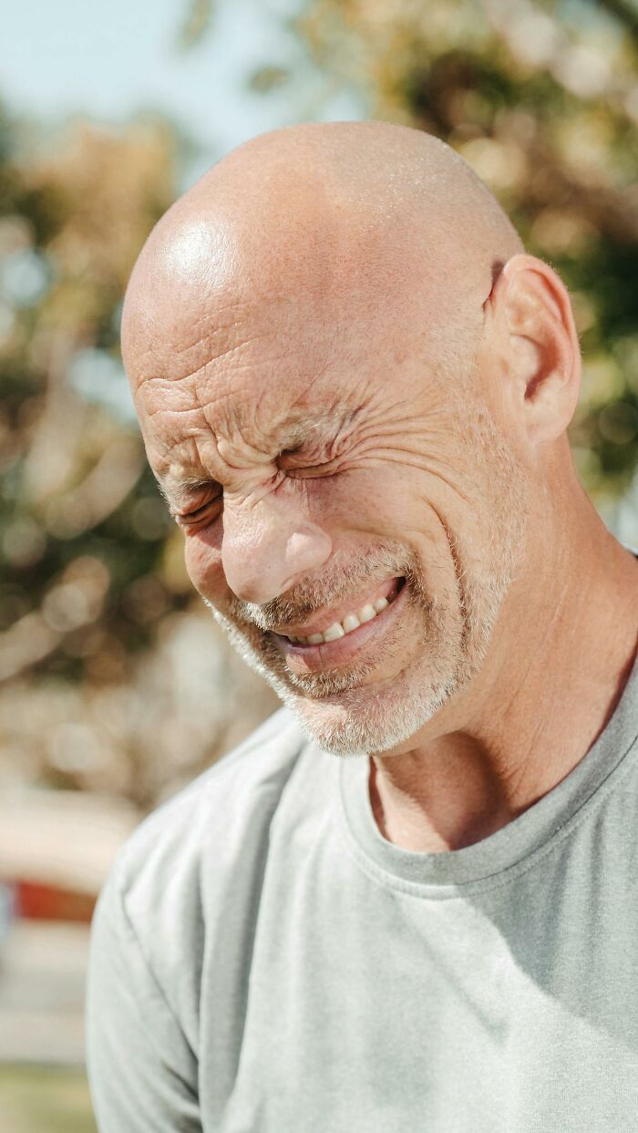 Bald man outdoors with eyes closed and smiling, reflecting on questions women would ask men without judgment.