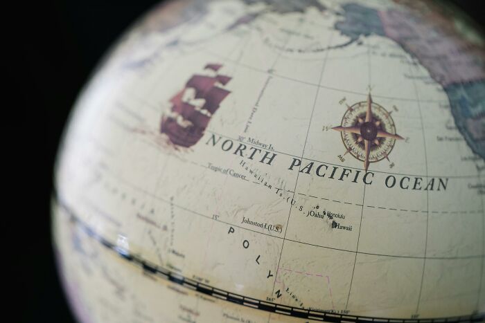 Close-up of a vintage globe showing the North Pacific Ocean and a compass rose, illustrating harsh life advice concepts.