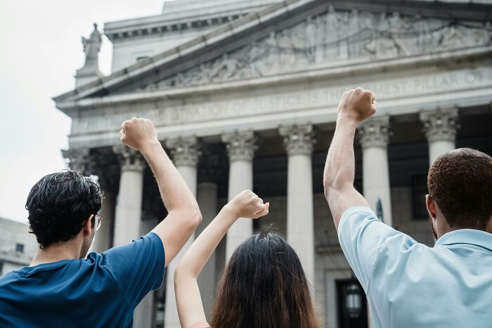 Three people with raised fists standing in front of a historic courthouse symbolizing biggest mistakes that changed history.