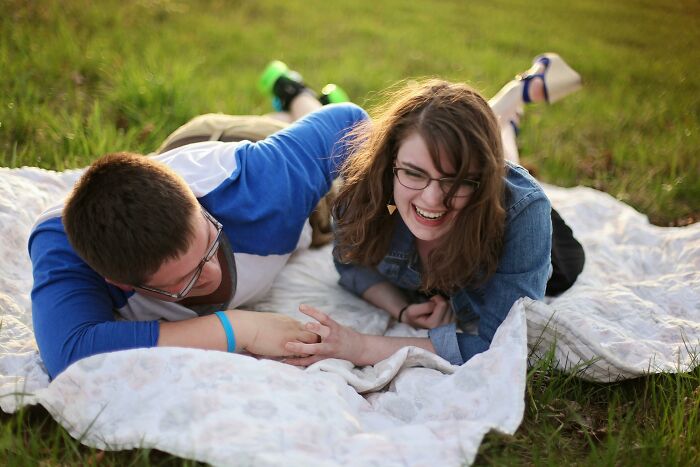 Couple laughing together on a blanket outside, capturing funny and weird moments girlfriends are secretly doing.
