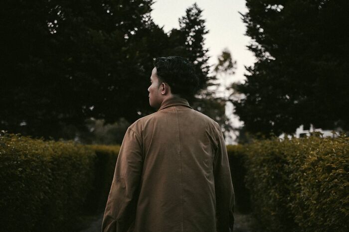 Man standing outdoors in a brown jacket looking away, conveying feelings related to women feeling instantly unsafe with a man.