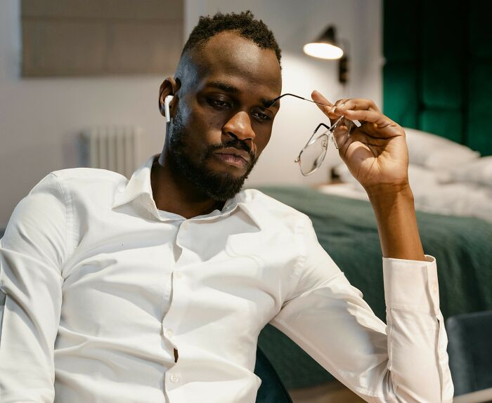 Man in white shirt holding glasses, reflecting thoughtfully on examples of placebo effect in real life situations.