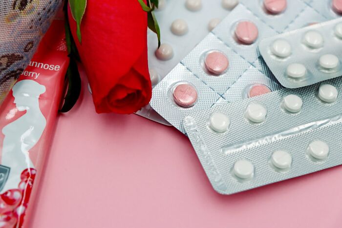Red rose and blister packs of pills on a pink surface representing improved quality of life and wellness products.