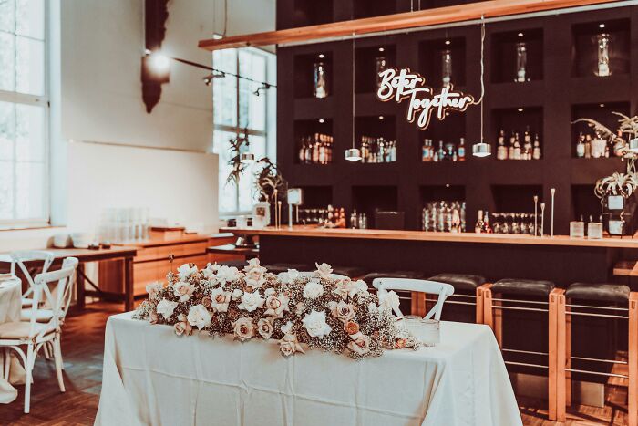 Stylish bar interior with wooden counters and floral centerpiece, perfect setting for bartenders sharing wildest tales.