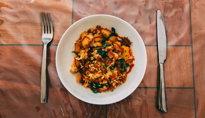 Bowl of cooked mixed vegetables and rice on a wooden table with fork and knife, illustrating absurd things people were told.