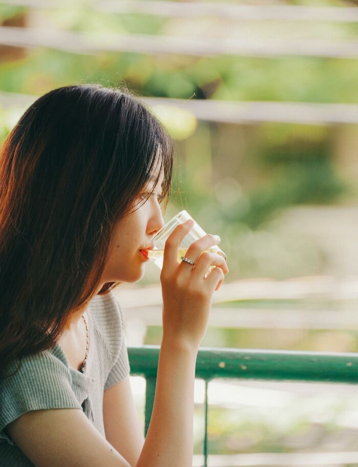 Young woman enjoying a peaceful moment drinking water, reflecting on lifestyle changes that improved quality of life.