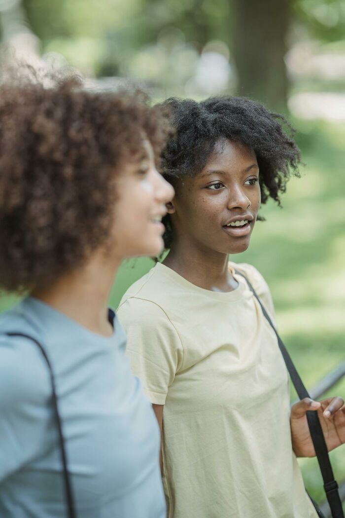 Two young women outdoors in casual wear, representing Gen Z discussing challenges of the middle class today.