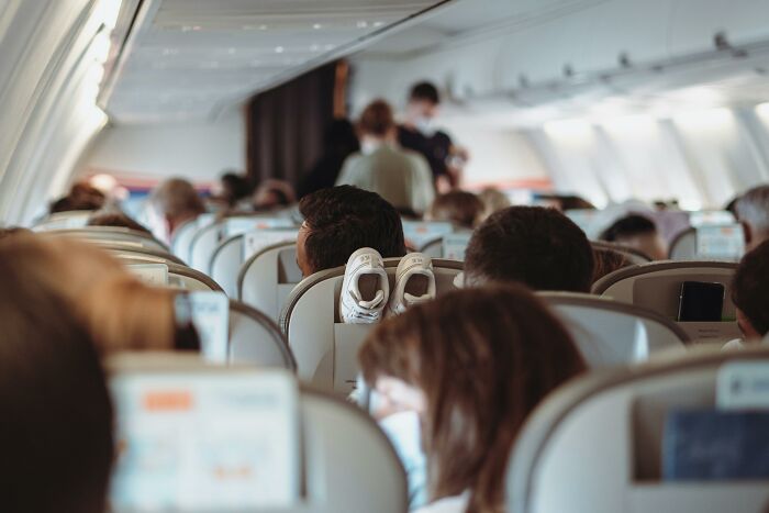 Passengers on a crowded airplane exhibiting common habits that are pure annoyance for flight attendants during the flight.