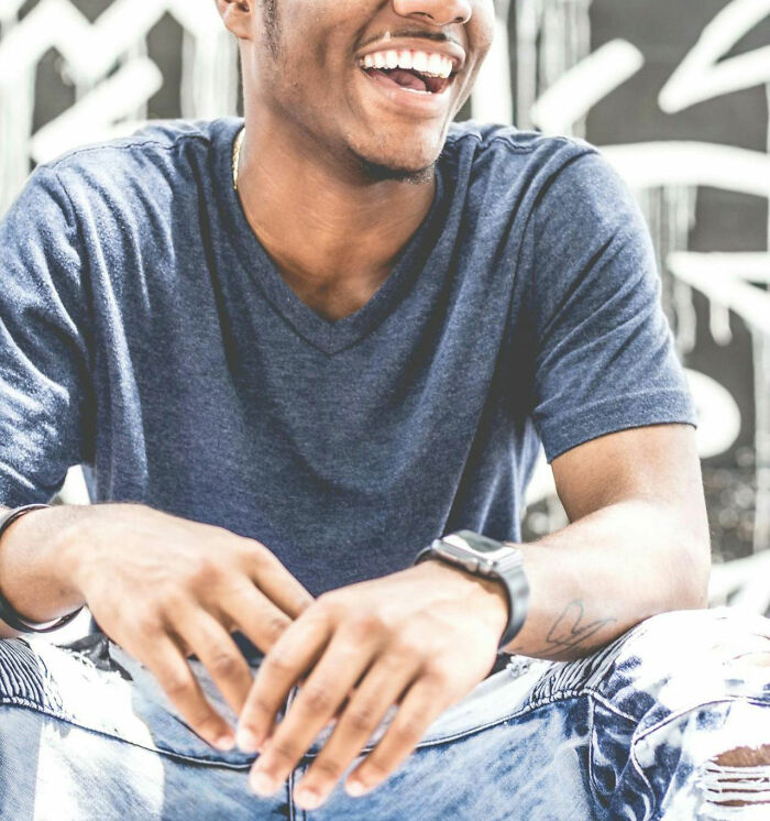 Young man wearing a blue shirt and watch, smiling and sitting casually, illustrating moments women felt instantly unsafe with a man.