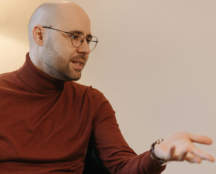 Man in glasses and a red turtleneck expressing strong emotions while discussing grandbaby as a sign from late wife.