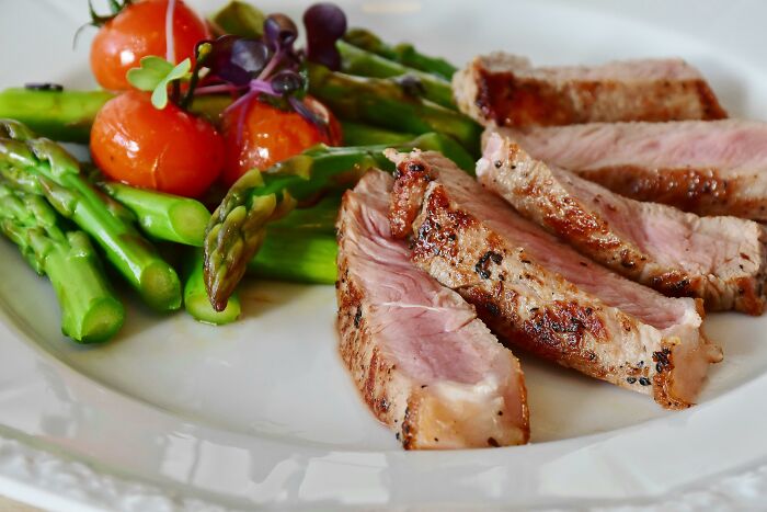 Grilled meat slices served with asparagus and cherry tomatoes, illustrating a meal shared by employees discussing strange recruiter comments.