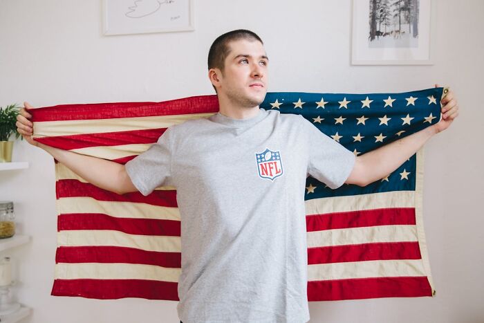 Man holding American flag behind him indoors, symbolizing shocking experiences people have lived through.
