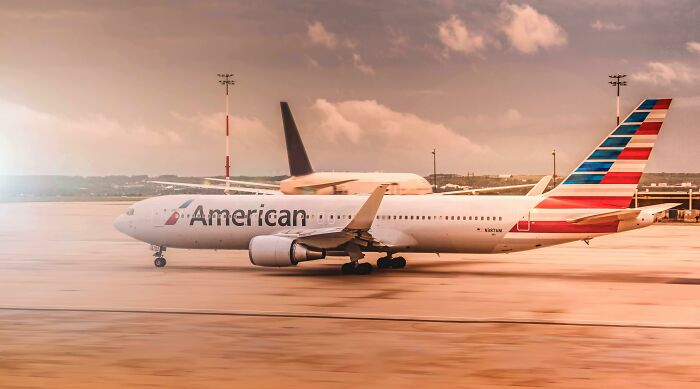 American Airlines airplane on runway at sunset with people share companies bad list concept background.